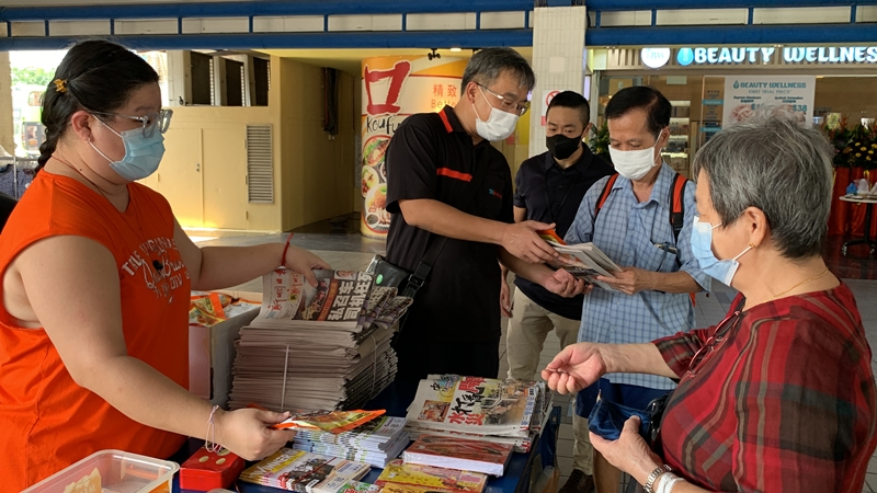 去年12月26日,《晚报》并入新明当天,本报总编辑朱志伟(左二)亲自到报摊与前来购买《新明》的读者交流。(档案照)